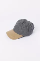 Gorra de béisbol gris con visera color tostado y parche decorativo.