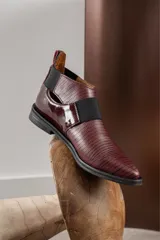 Bota corta color borgoña con textura de reptil, puntera fina, elástico negro en el empeine y talón descubierto.