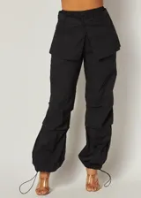 Pantalón cargo negro con cintura elástica, corte holgado, bolsillos laterales y detalle de falda superpuesta en la parte delantera.