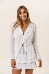 Blusa blanca de manga larga con cuello camisero y lazo en la cintura.