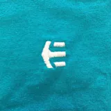 Remera color mostaza con logo de la marca Etnies estampado en el pecho.