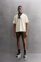 Camiseta deportiva marrón con estructura perforada, cuello redondo, manga corta y logo estampado.