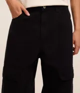 Pantalón de hombre de corte super baggy confeccionado en sarga de poliéster y algodón color negro, con bolsillos cargo laterales, cintura con trabillas y cierre de cremallera.