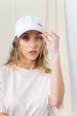 Gorra blanca de algodón con visera curva y logo de Peach bordado en el frente.