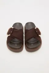 Sandalias bajas color verde oliva con tiras cruzadas de gamuza sintética y hebilla dorada.