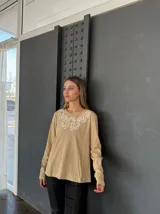Remera blanca de manga larga con cuello redondo y bordado floral en el pecho.