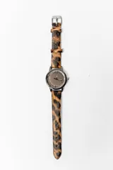 Reloj de pulsera con caja metálica color plomo, esfera marrón con números arábigos y correa de cuero sintético con estampado animal print.
