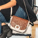 Morral en cuero vacuno bicolor, con bolsillo trasero con cierre y correa ajustable y removible.