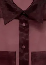 Camisa de organza color borgoña, de corte recto, manga larga con puños abotonados, cuello camisero, cierre frontal con botones y dos bolsillos de parche en la parte delantera.