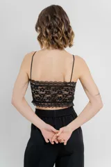 Top crop negro de cuero ecológico con espalda de encaje floral nude, tirantes finos y corte entallado.