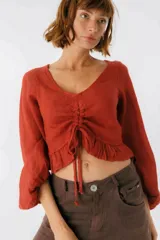 Blusa blanca de lino con escote en V, mangas largas abullonadas y frunce central.