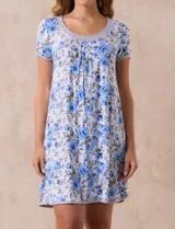 Camisón corto de tejido suave con estampado floral en tonos celeste y azul. Tiene mangas cortas, escote redondo con ribete gris y detalle plisado en el delantero.