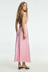 Vestido largo color rosa pálido, con escote en V pronunciado y tirantes finos tipo espagueti que se unen en la espalda. El corte es recto y holgado, con caída fluida.