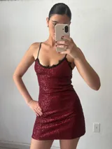 Vestido corto de fiesta color bordó, con lentejuelas, breteles finos y escote con encaje negro.