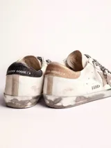 Zapatillas Golden Goose modelo Super-Star, de cuero blanco con efecto desgastado. Estrella de gamuza color beige en el lateral exterior y contrafuerte de cuero metalizado color dorado. Cordones con estampado animal print.