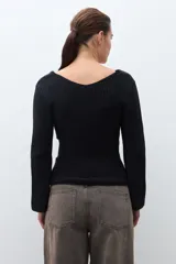 Sweater de tejido de punto negro, con escote en V pronunciado y mangas largas acampanadas. Presenta un lazo ancho anudado a la cintura.