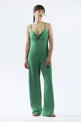 Mono largo negro de breteles finos, con escote cruzado y abertura en el abdomen. Pantalón de corte palazzo.