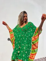 Túnica corta verde con estampado de flores blancas y detalles bordados en el escote. Mangas anchas con terminación en tela estampada a rayas naranjas y blancas.