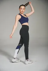 Calza deportiva larga negra con recortes geométricos en blanco y azul en la parte inferior de la pierna.