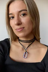 Collar con doble tira de tiento negro, una ajustada al cuello como choker y otra más larga con un dije ovalado de piedra natural blanca y un pequeño detalle dorado.