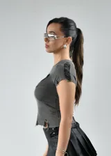 Remera gris de tejido de punto acanalado con cuello redondo, mangas cortas con borde desflecado, logo en el frente y ruedo irregular con terminación desflecada.