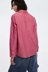 Camisa a rayas verticales rojas y blancas, de corte recto, con cuello clásico, manga larga y bolsillo en el pecho.