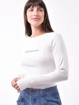 Remera blanca de manga larga con cuello redondo y estampado pequeño con la frase 'Busy ignoring someone' en el pecho.