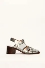 Sandalias plateadas de cuero con tiras entrecruzadas y hebilla lateral. Taco de madera de 6 cm.