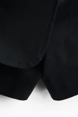 Short pollera negro de tiro alto, cruzado y con botón a un lado. Confeccionado en sarga de algodón, con cierre oculto adelante y bolsillos insertados decorativos atrás.
