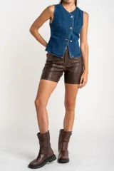 Chaleco de denim azul con cierre cruzado con botones metálicos.