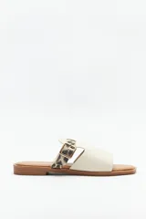 Sandalias bajas color crema, con suela acolchada y pequeño taco de 2cm. Capellada de símil cuero texturizado con tira en animal print y hebilla ajustable.