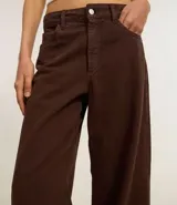 Pantalón recto loose confeccionado en sarga de algodón BCI color marrón, con bolsillos delanteros y traseros, cierre con botón y cremallera.