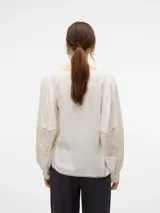 Camisa blanca de mangas largas abullonadas con detalle de bordado en las mangas y escote en V.