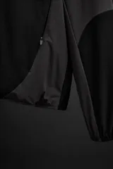 Cazadora con capucha confeccionada en tejido técnico ligero y elástico en todas las direcciones, color negro con detalles en gris. Cuenta con cuello con capucha ajustable, manga larga, bolsillos con cierre de cremallera en cadera, acabados con elástico y cierre frontal de cremallera.