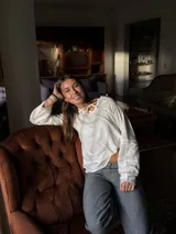 Camisa blanca de manga larga con escote a la base y detalles de blonda en cuello y mangas.