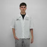 Camisa blanca de manga corta con cuello tipo cubano, corte oversize y estampado con el logo de la marca en el pecho y la espalda.