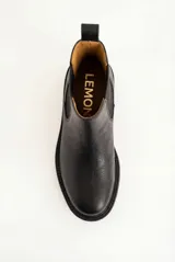 Bota tipo Chelsea de cuero negro con paneles elásticos laterales, tirador trasero y suela de goma con taco bajo.