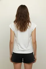 Remera negra de algodón con cuello redondo y mangas cortas. Presenta un estampado abstracto con apliques de strass dorados.