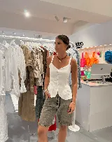 Chaleco blanco de lino, con tirantes anchos y cierre frontal de botones. Presenta un corte ajustado con un ruedo inferior festoneado.