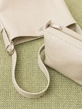 Cartera tipo tote confeccionada en cuero vacuno color crudo, con textura tipo piel de cocodrilo. Tiene correa larga al hombro y apliques metálicos con el logo de la marca. Incluye sobre interno desmontable con cierre.