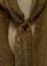 Blusa de tejido fluido color verde con estampado paisley, escote de pico con lazo, mangas largas con puños abotonados y corte recto.