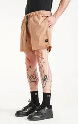 Short de baño color beige con cintura elástica y cordón ajustable. Cuenta con tres bolsillos y un parche con logo en la pierna izquierda.