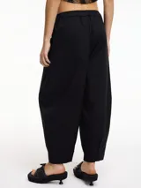 Pantalón negro tipo chino con pinzas delanteras, bolsillos laterales y pretina con elástico.