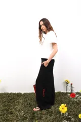 Pantalón blanco de lino, de corte amplio y tiro medio/bajo. Tiene bolsillos delanteros y traseros, botón metálico grabado y bordados laterales y traseros.