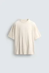 Camiseta color crema de corte holgado, confeccionada en tejido con textura arrugada y cuello redondo.