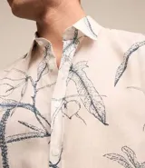 Camisa de hombre confeccionada en voil color crudo con estampa floral estilo outline en azul. Tiene cuello inglés, abotonado delantero y manga corta.