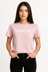 Remera manga corta color rosa con estampado frontal con la frase "I'm just a girl" en letras blancas, de corte holgado y cuello redondo.