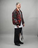 Campera reversible negra con estampado abstracto en rojo y blanco, de corte amplio y cuello camisero.