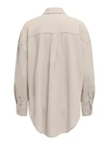 Camisa oversize color beige, con cuello clásico, mangas largas con puños abotonados, cierre frontal con botones y bolsillo de parche en el pecho.