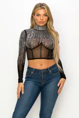 Top tipo corset de tul elastizado semi transparente color negro, con cuello alto y mangas largas. Cubierto con pedrería plateada.